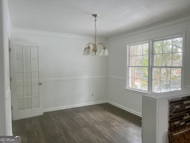 unfurnished dining area featuring ornamental molding, dark hardwood / wood-style floors, and a chandelier