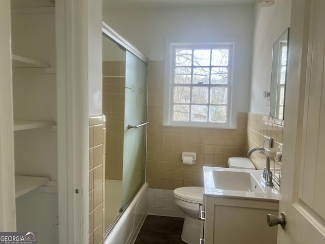 full bathroom featuring enclosed tub / shower combo, vanity, toilet, and tile walls