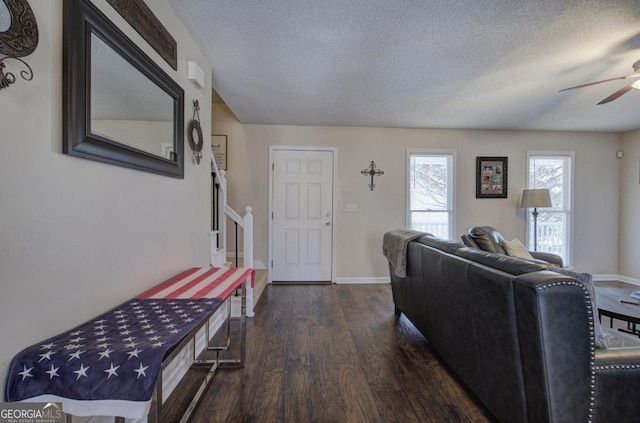 living room featuring ceiling fan, dark wood-type flooring, and a textured ceiling