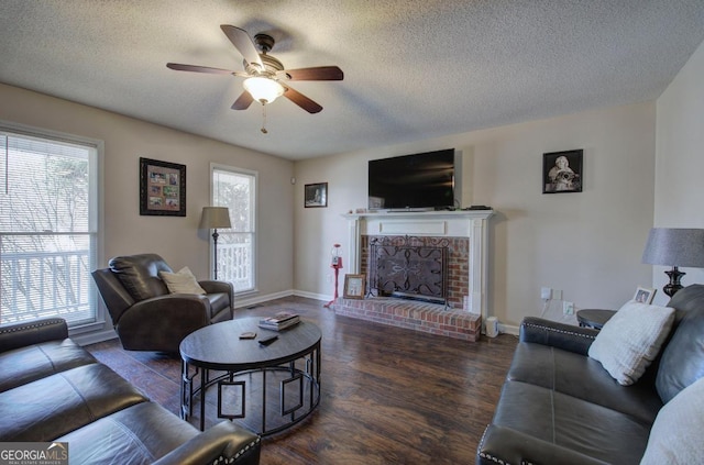 living room featuring ceiling fan, a fireplace, dark hardwood / wood-style floors, and a textured ceiling