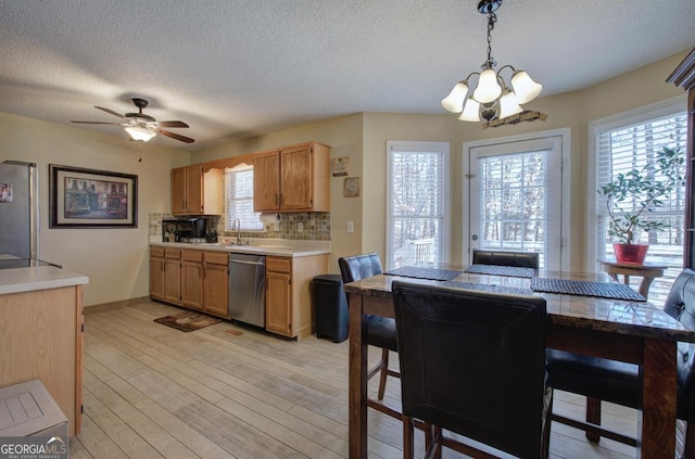 kitchen featuring a textured ceiling, appliances with stainless steel finishes, pendant lighting, light hardwood / wood-style floors, and decorative backsplash