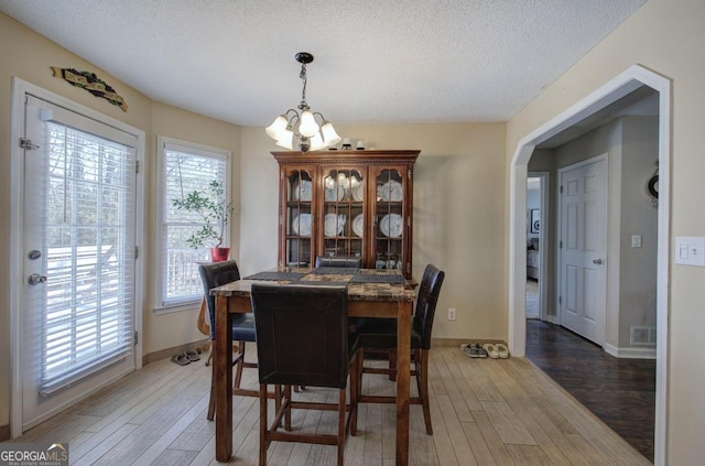 dining room with hardwood / wood-style flooring, a chandelier, and a textured ceiling