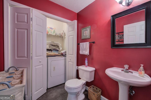 bathroom with washer / dryer, a textured ceiling, and toilet