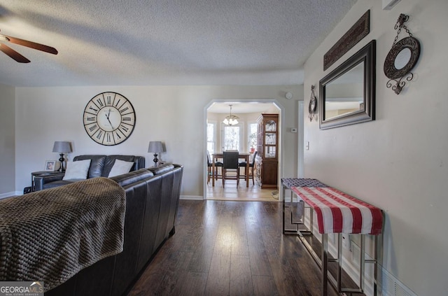 living room featuring ceiling fan, dark wood-type flooring, and a textured ceiling