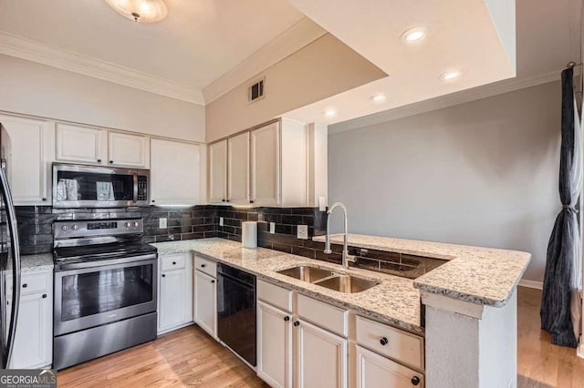 kitchen with appliances with stainless steel finishes, tasteful backsplash, sink, light stone counters, and kitchen peninsula