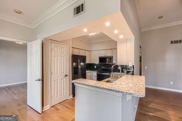 kitchen featuring sink, light stone counters, appliances with stainless steel finishes, kitchen peninsula, and white cabinets