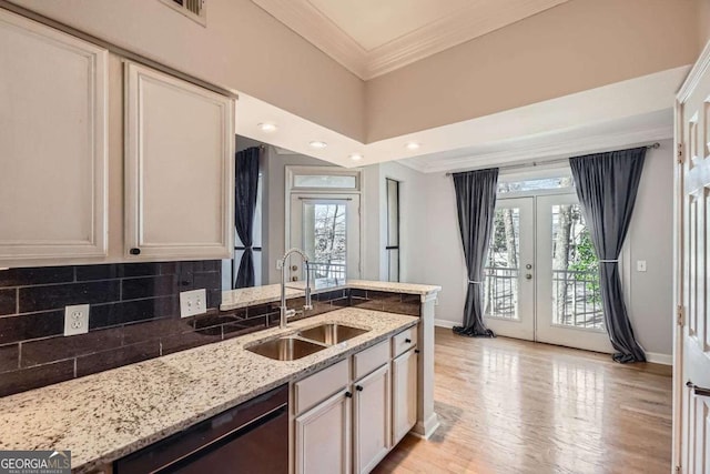 kitchen with sink, dishwashing machine, light stone counters, crown molding, and french doors