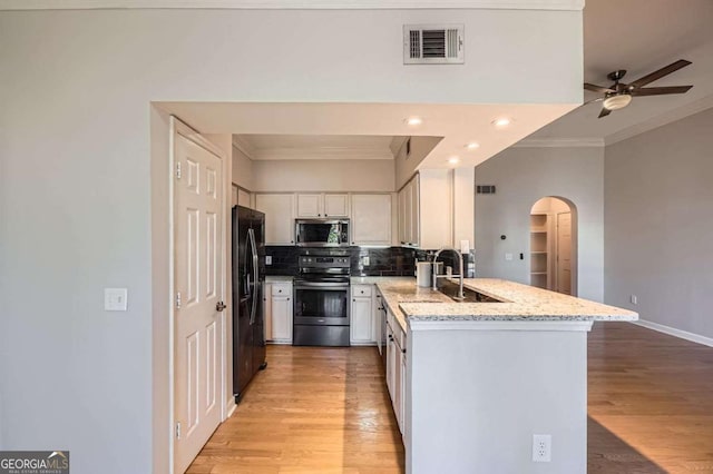 kitchen with sink, white cabinetry, stainless steel appliances, tasteful backsplash, and light stone countertops