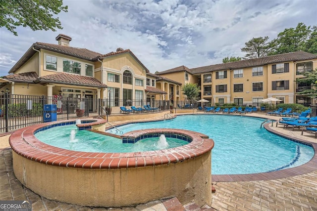 view of pool with pool water feature, a community hot tub, and a patio