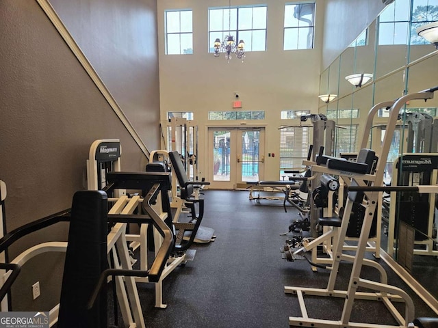 exercise room featuring a towering ceiling, a wealth of natural light, and french doors