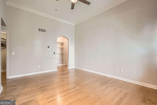 spare room featuring ceiling fan, a towering ceiling, crown molding, and light hardwood / wood-style floors