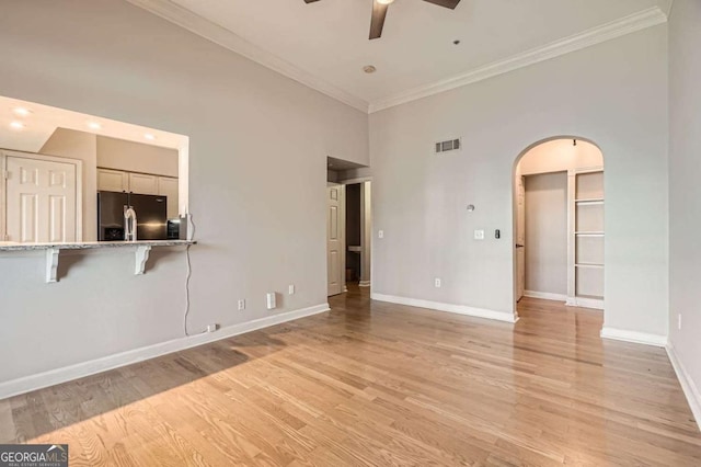 unfurnished living room with crown molding, light hardwood / wood-style floors, ceiling fan, and a high ceiling