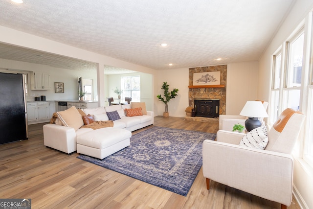 living room featuring a textured ceiling, a healthy amount of sunlight, and light wood-type flooring