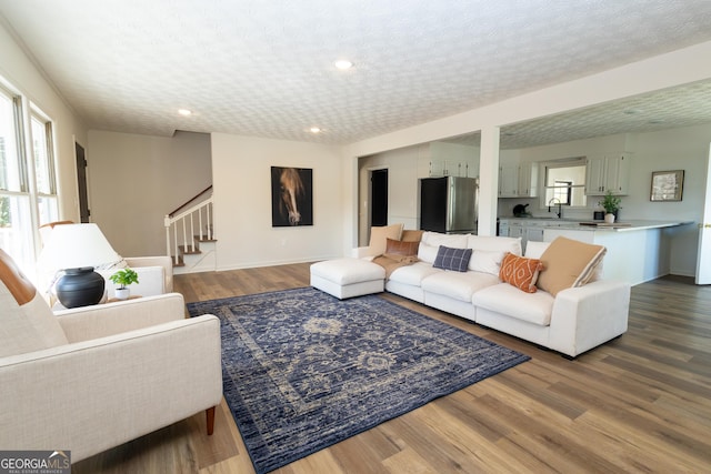 living room featuring wood-type flooring, sink, and a textured ceiling