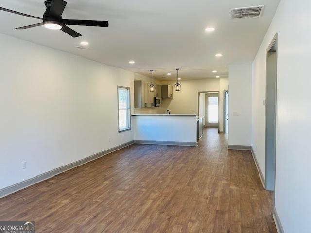 unfurnished living room featuring dark hardwood / wood-style floors and ceiling fan