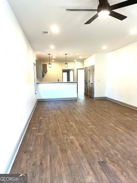 unfurnished living room with dark hardwood / wood-style floors and ceiling fan