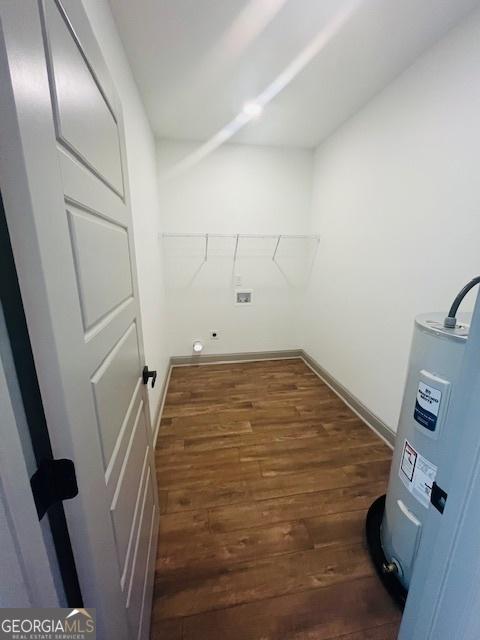 clothes washing area featuring dark hardwood / wood-style floors and water heater