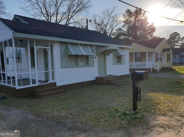 bungalow-style house with a sunroom and a front lawn