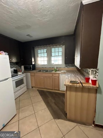 kitchen with sink, white appliances, light tile patterned floors, and a textured ceiling