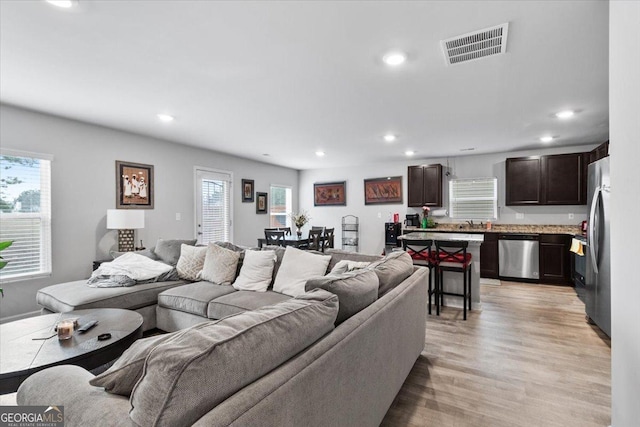 living room with recessed lighting, visible vents, and light wood-style floors