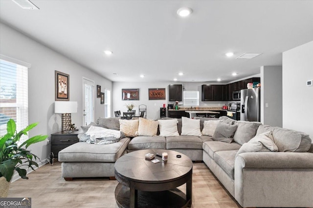 living area with light wood finished floors, plenty of natural light, and recessed lighting