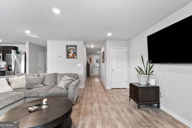 living room featuring light wood-style flooring, visible vents, baseboards, and recessed lighting