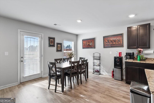 dining area with light wood-style floors, visible vents, and baseboards