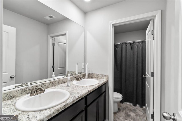 full bath featuring toilet, double vanity, visible vents, and a sink