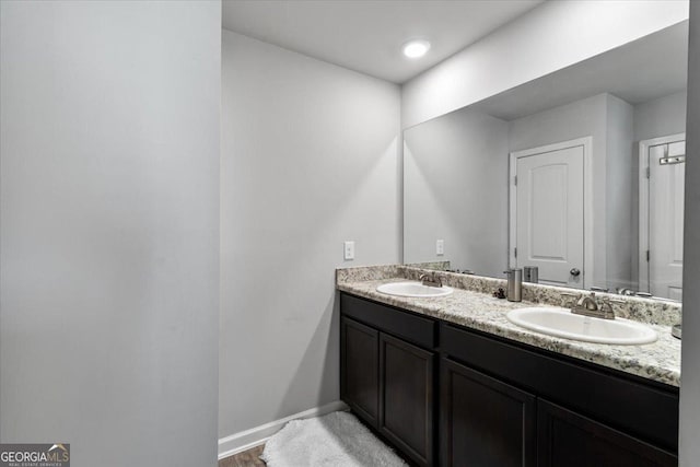 full bath with a sink, baseboards, and double vanity