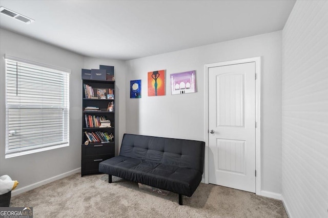 living area featuring light colored carpet, visible vents, and baseboards