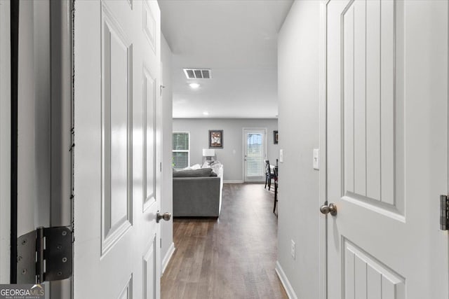 hallway featuring dark wood-style floors, baseboards, and visible vents