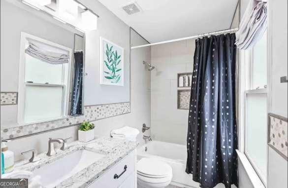 full bathroom featuring shower / tub combo, vanity, a wealth of natural light, and toilet