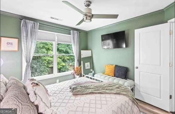 bedroom with hardwood / wood-style flooring, ceiling fan, and crown molding