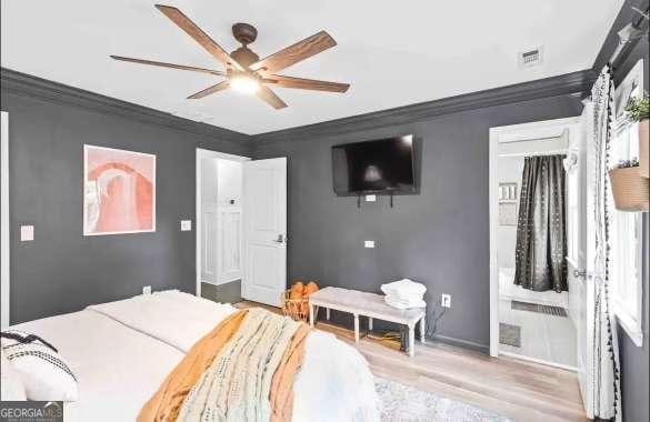 bedroom featuring ceiling fan, ornamental molding, and light wood-type flooring