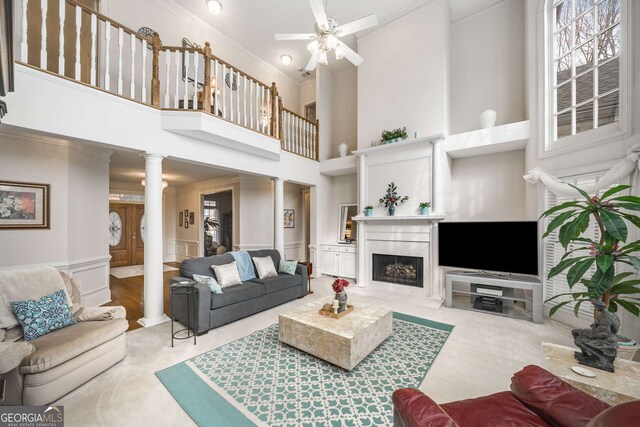 2290 Spencers Way, Stone Mountain, GA 30087 - living room with decorative columns, a ceiling fan, a high ceiling, a fireplace with flush hearth, and crown molding