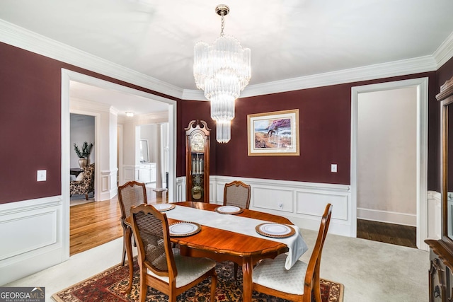 dining space with hardwood / wood-style flooring, crown molding, and a chandelier