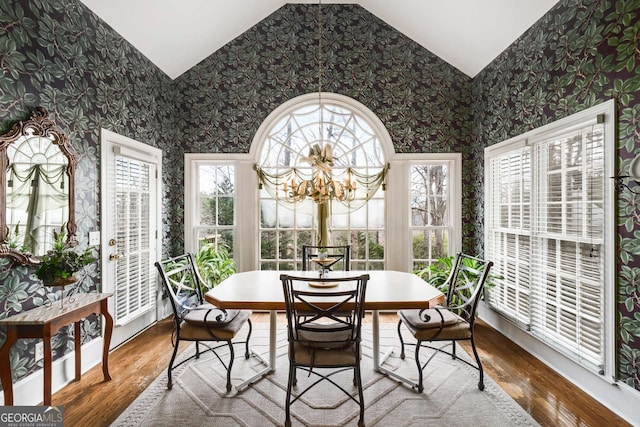 sunroom / solarium with wood-type flooring, vaulted ceiling, and a notable chandelier