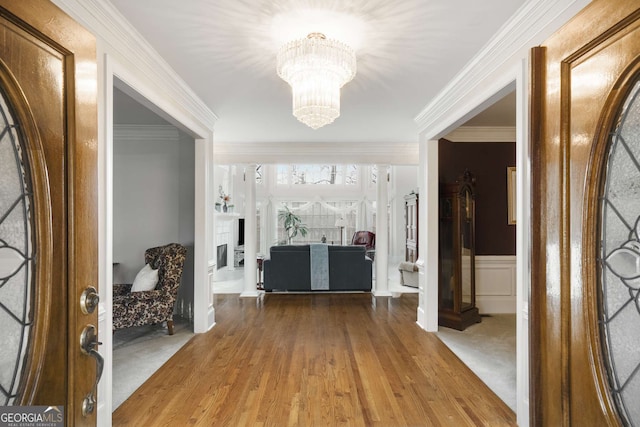 entrance foyer with a notable chandelier, crown molding, and hardwood / wood-style flooring