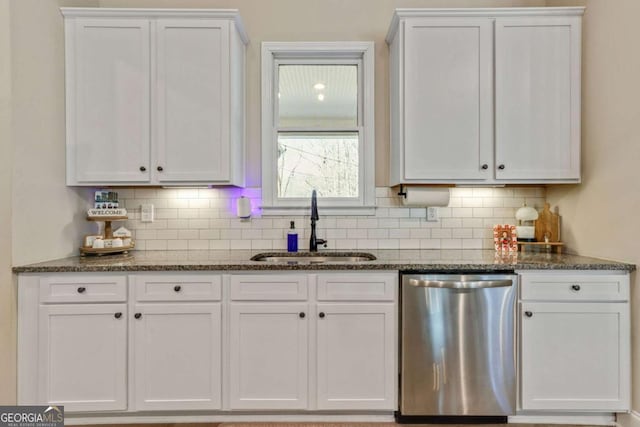 kitchen featuring white cabinetry, sink, stainless steel dishwasher, and dark stone counters