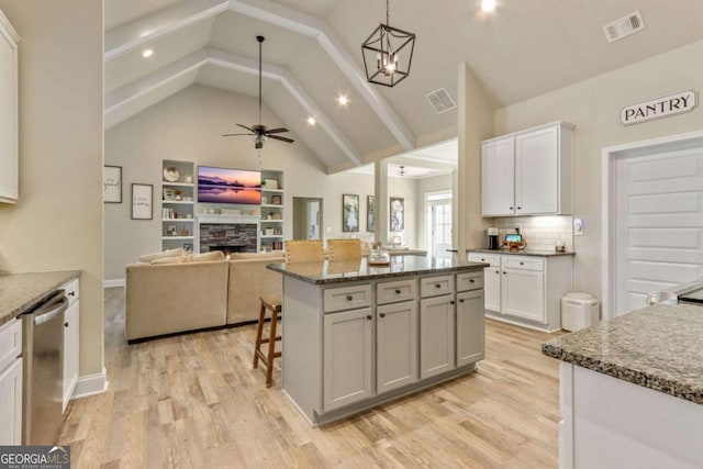 kitchen with pendant lighting, tasteful backsplash, white cabinets, a kitchen island, and stainless steel dishwasher