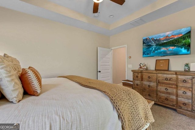 carpeted bedroom featuring a tray ceiling and ceiling fan