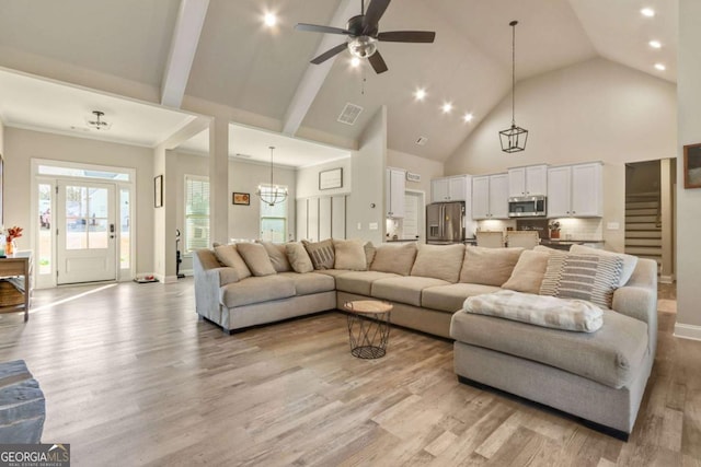 living room featuring ceiling fan with notable chandelier, high vaulted ceiling, and light wood-type flooring