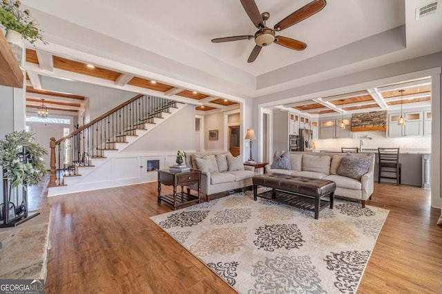 living room featuring beamed ceiling, coffered ceiling, hardwood / wood-style floors, and ceiling fan