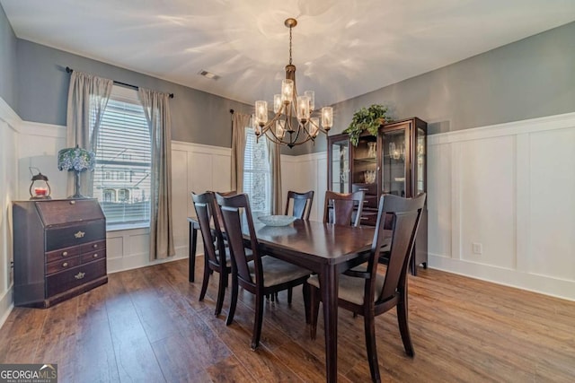 dining space with hardwood / wood-style flooring and a notable chandelier