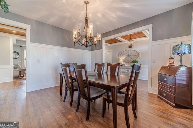 dining area featuring beamed ceiling, hardwood / wood-style floors, and an inviting chandelier