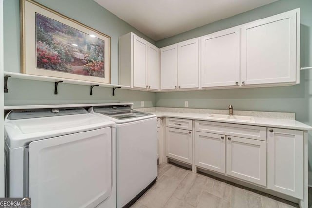 laundry area with cabinets, washing machine and dryer, sink, and light hardwood / wood-style flooring