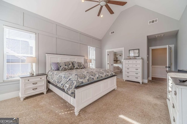 bedroom with connected bathroom, high vaulted ceiling, light colored carpet, and ceiling fan