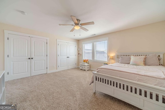 bedroom with carpet, two closets, and ceiling fan