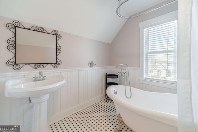 bathroom featuring vaulted ceiling and a tub