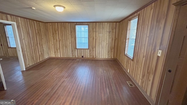 empty room with ornamental molding, dark hardwood / wood-style floors, and wood walls